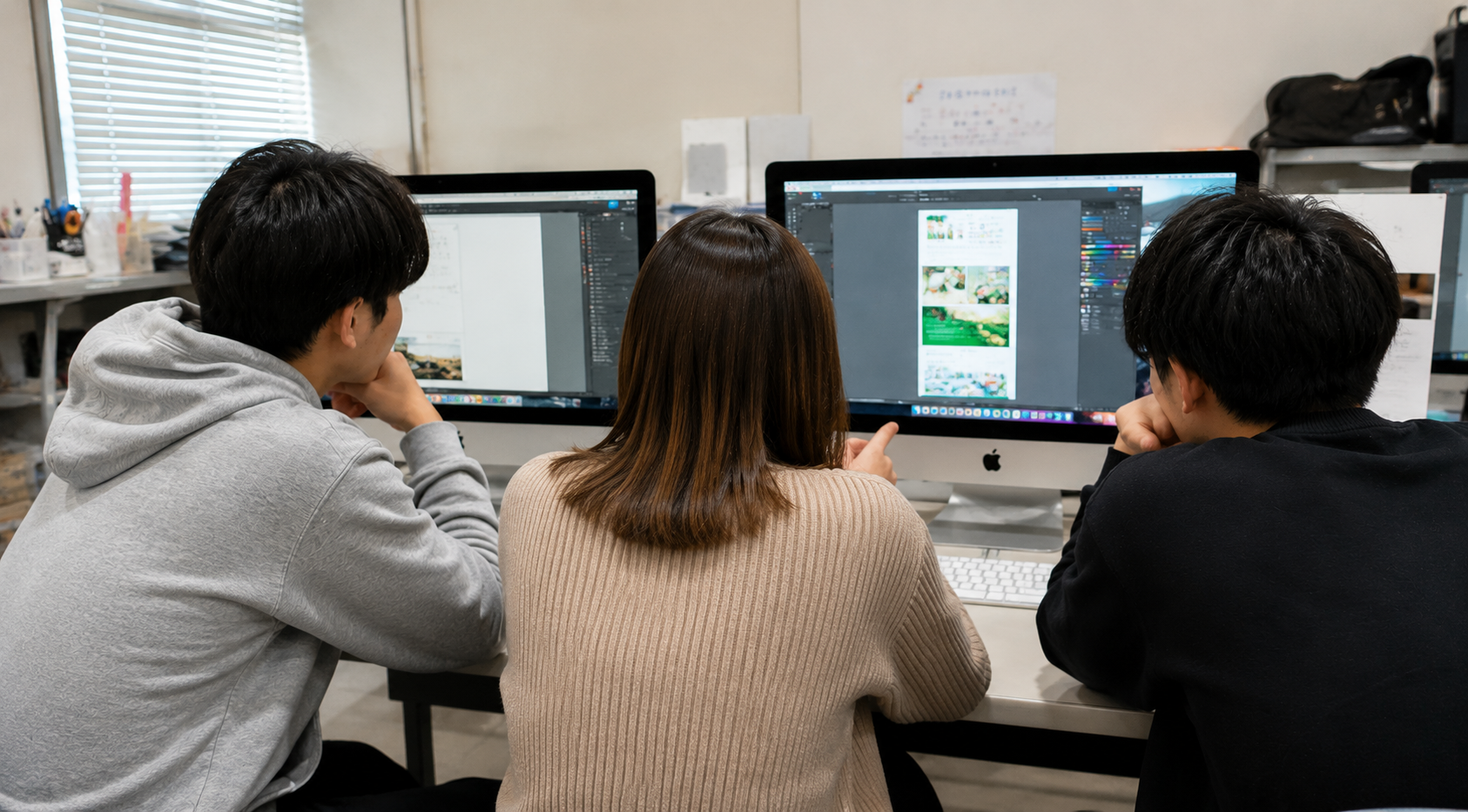 顔を強調せず、複数人でMacを使った制作に取り組むイメージ