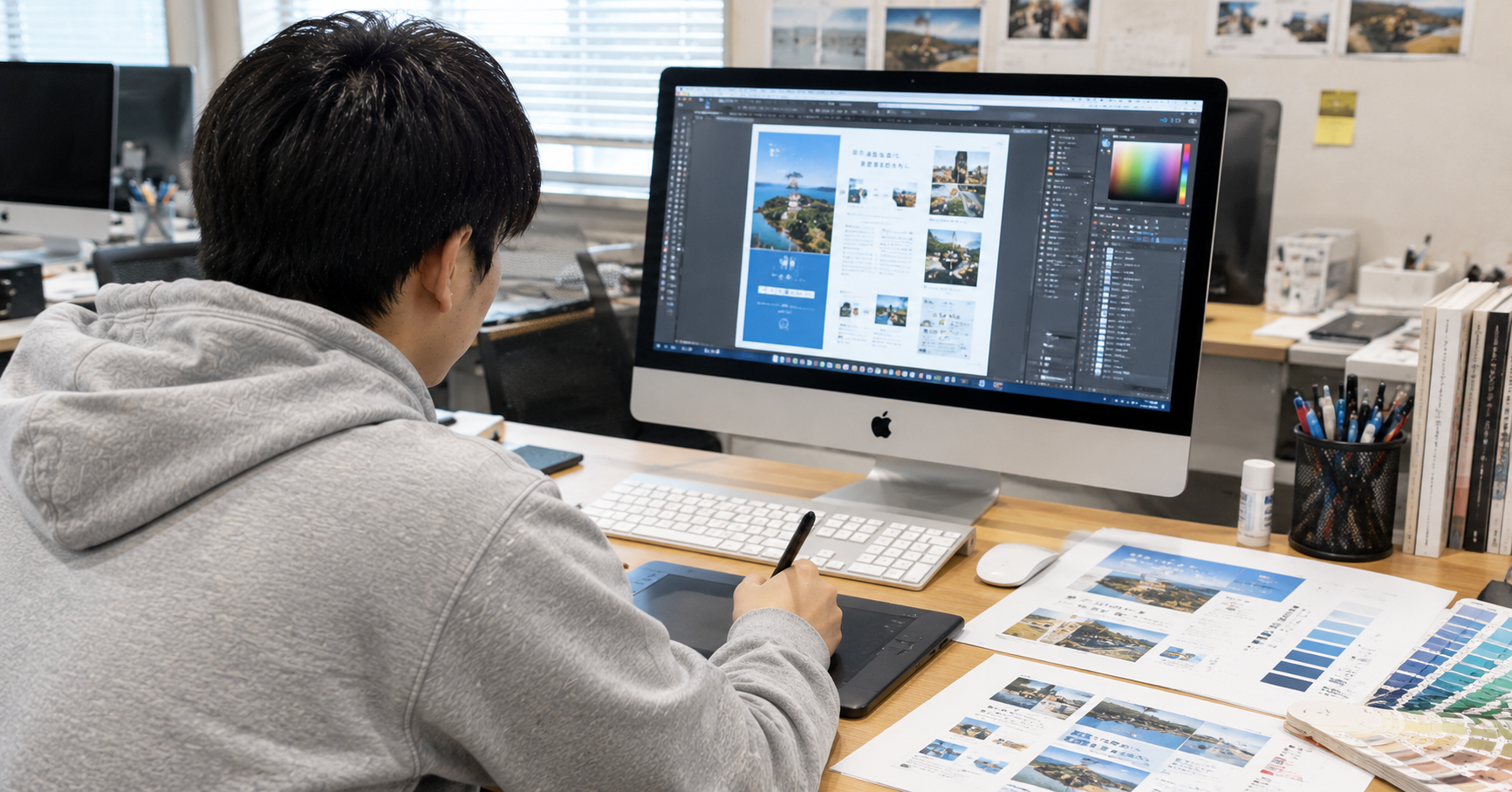 Macの前でDTPデザインを制作する様子